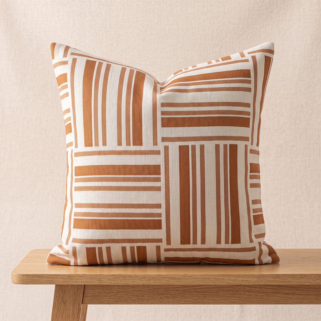 Geometric Throw Pillow Cover – Jacquard in Rust – Patchwork Stripe – standing upright on a light wooden bench against a cream wall