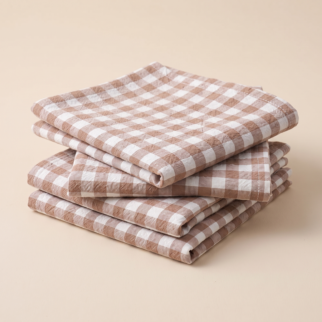 Gingham Cloth Napkins – Set of 4 in Beige Gingham – stacked in a neat pile on a plain peach background