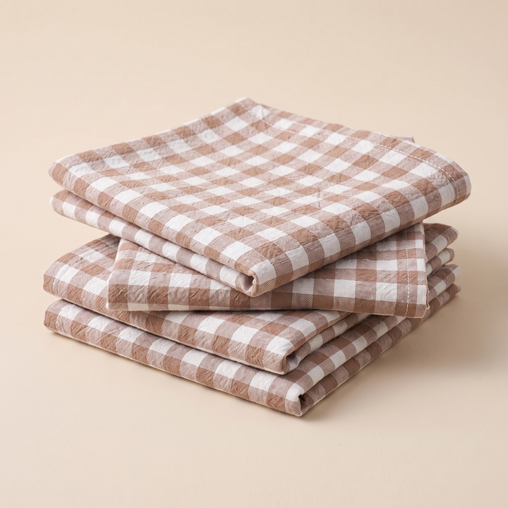 Gingham Cloth Napkins – Set of 4 in Beige Gingham – stacked in a neat pile on a plain peach background