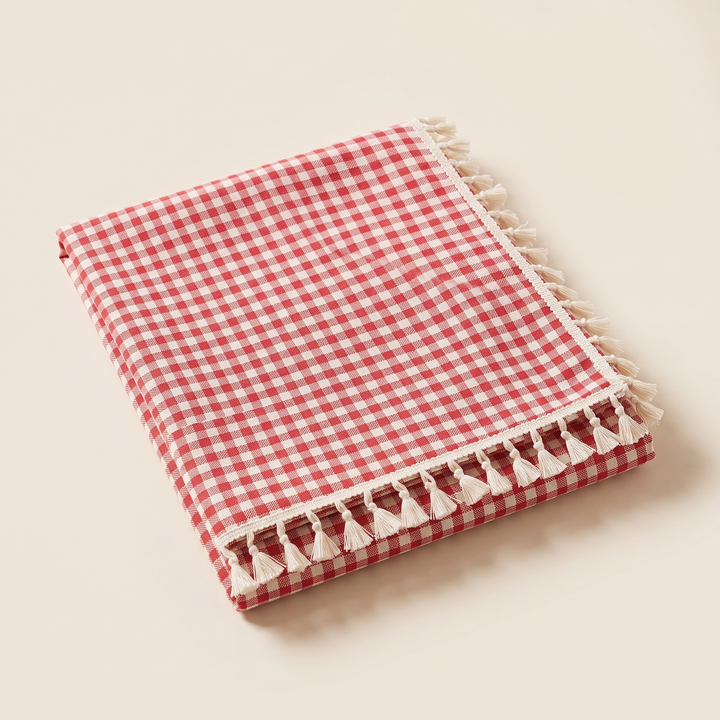 Red Gingham Tablecloth with Tassels in Red – Gingham – folded neatly on a plain cream background, tassels along edge