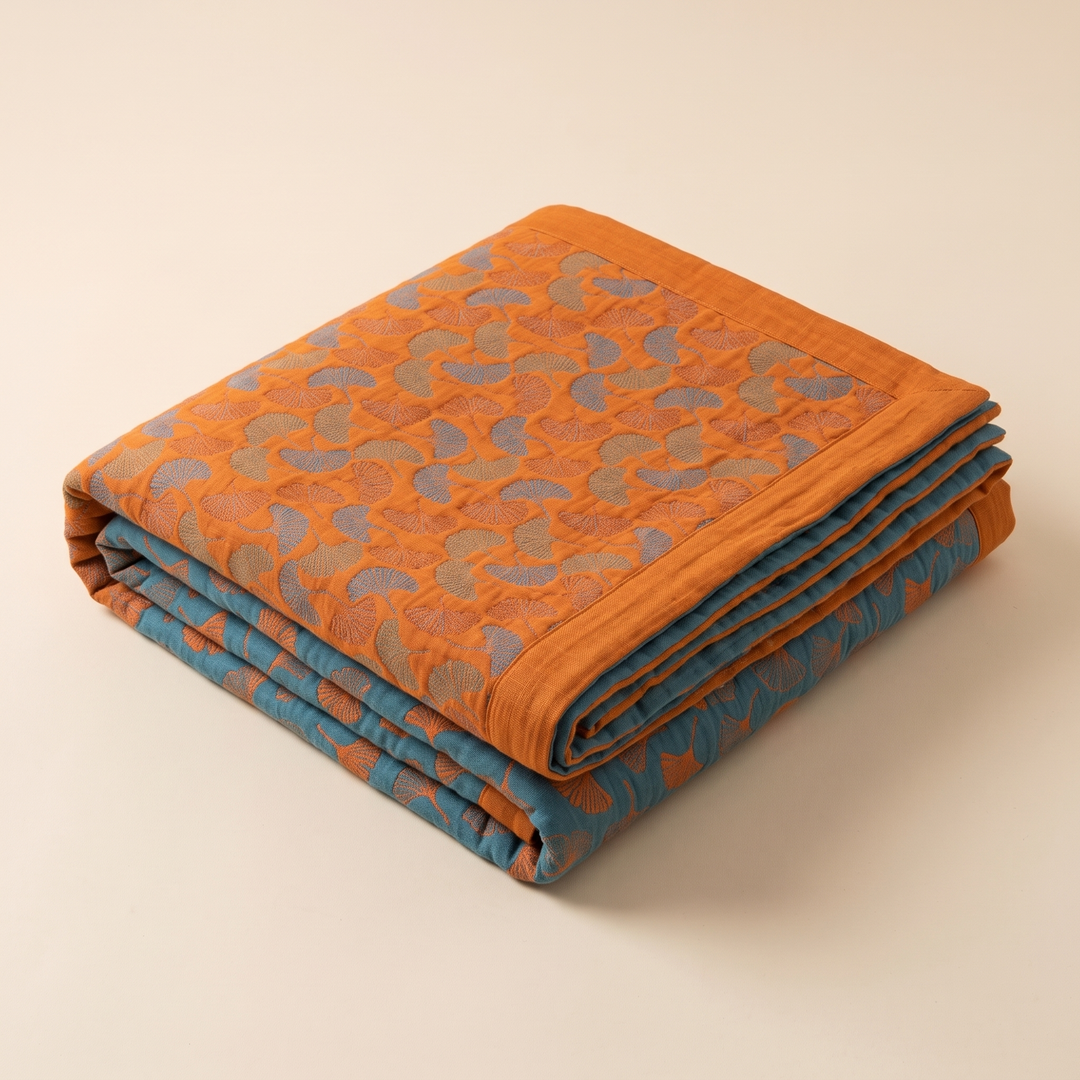 Ginkgo Leaf Gauze Blanket in Orange – folded in a neat stack on a plain cream background
