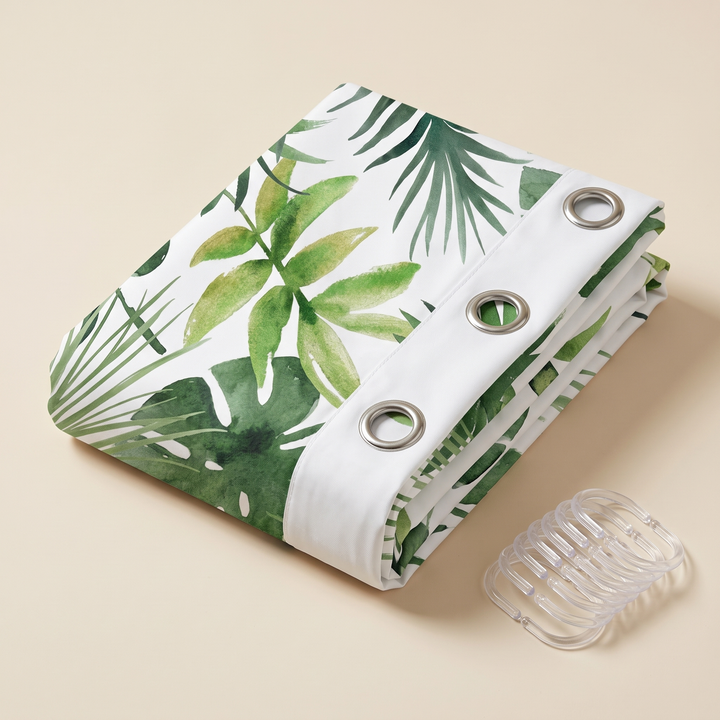 Greenery Shower Curtain – Watercolor Leaves in Green – Tropical – folded on a beige surface beside clear shower hooks