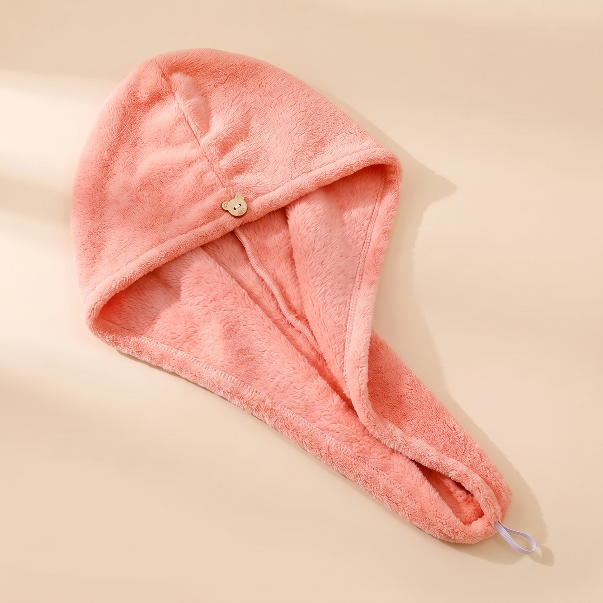 Hair Wrap Towel – Turban Style in Pink – laid flat on a plain beige surface with button loop visible