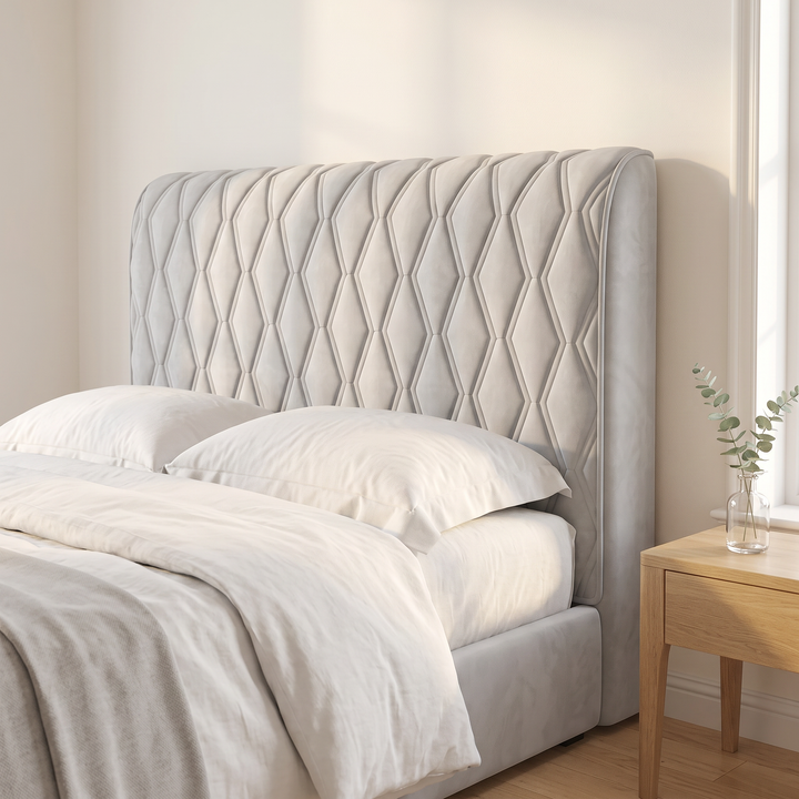 Quilted Headboard Cover – Padded in Light Gray – beside a glass vase of eucalyptus and layered bedding