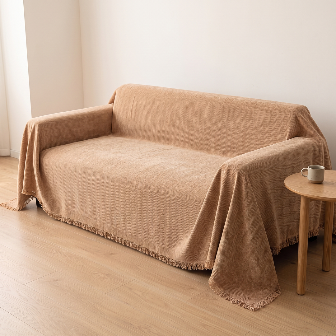 Herringbone Chenille Couch Cover with Fringe in Camel – beside a wooden stool with a speckled mug