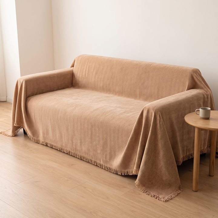 Herringbone Chenille Couch Cover with Fringe in Camel – beside a wooden stool with a speckled mug