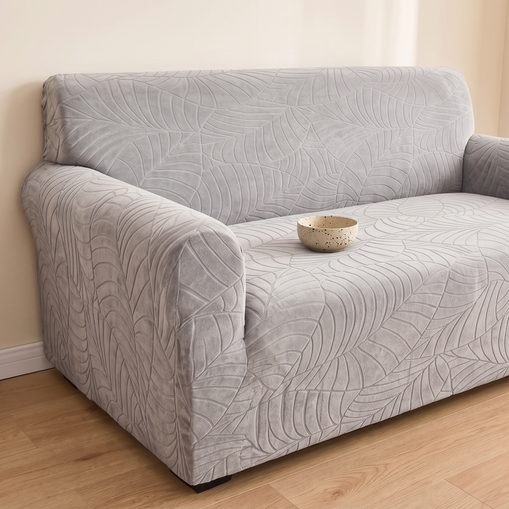Jacquard Stretch Sofa Cover in Light Gray – with a speckled ceramic bowl resting on the seat