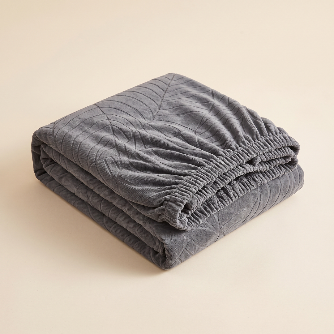 Jacquard Stretch Sofa Cover in Dark Gray – folded neatly with elastic hem edge visible on a beige background