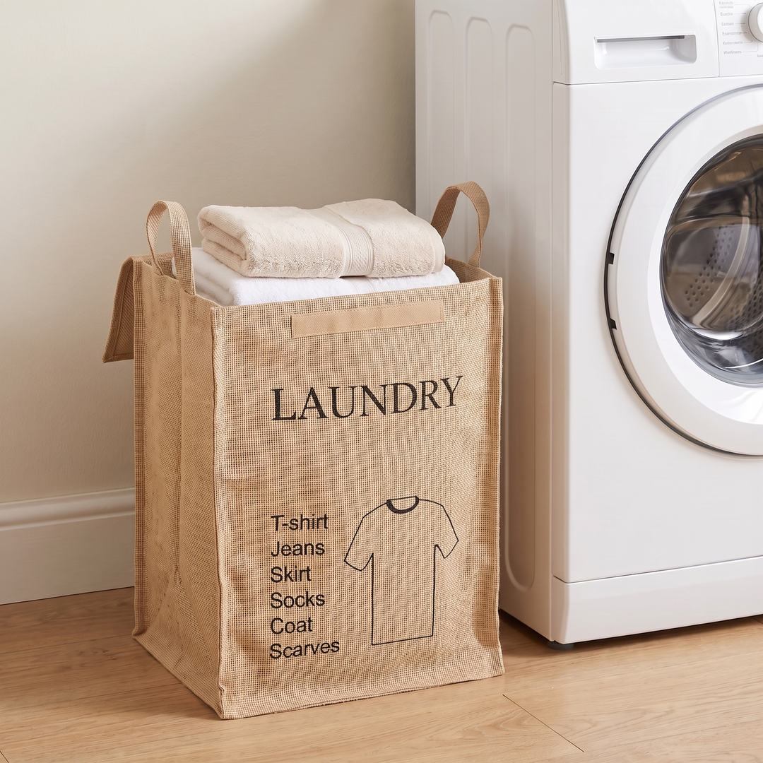 Jute Storage Basket with Lid – Foldable in Natural – Laundry Shirt – filled with folded towels beside a washing machine on wood flooring