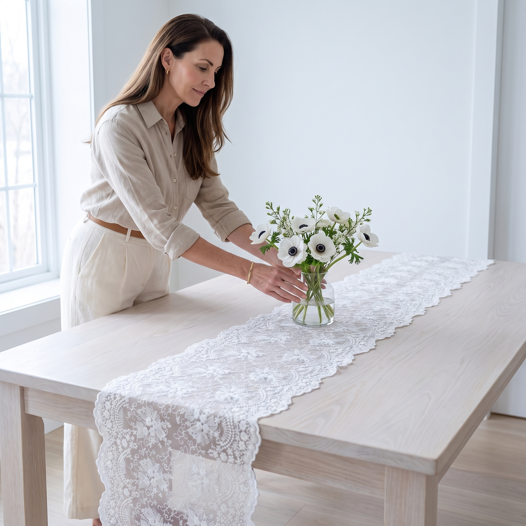 Lace Table Runner in White – woman placing a flower vase on a wooden table