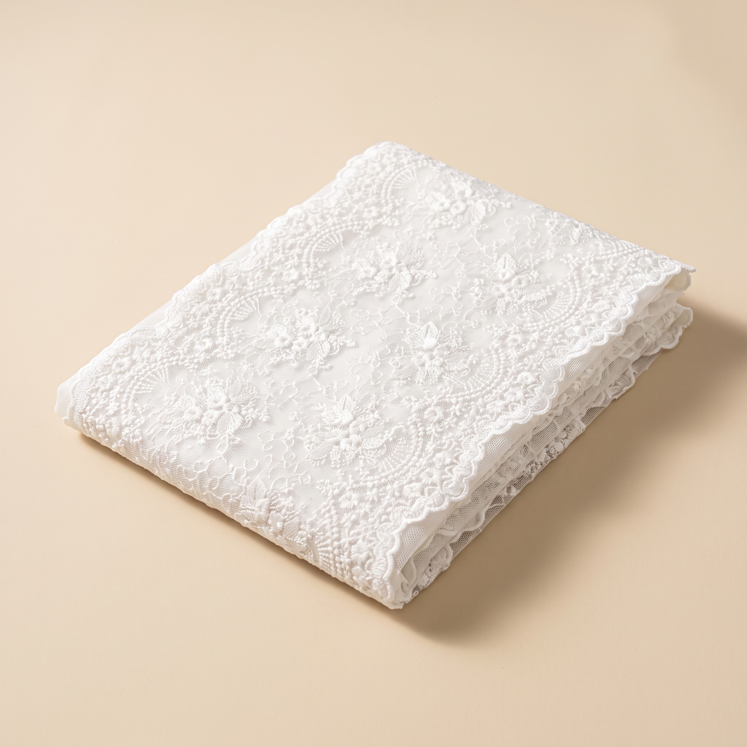 Lace Table Runner in White – folded neatly on a plain beige background, seen from above at an angle