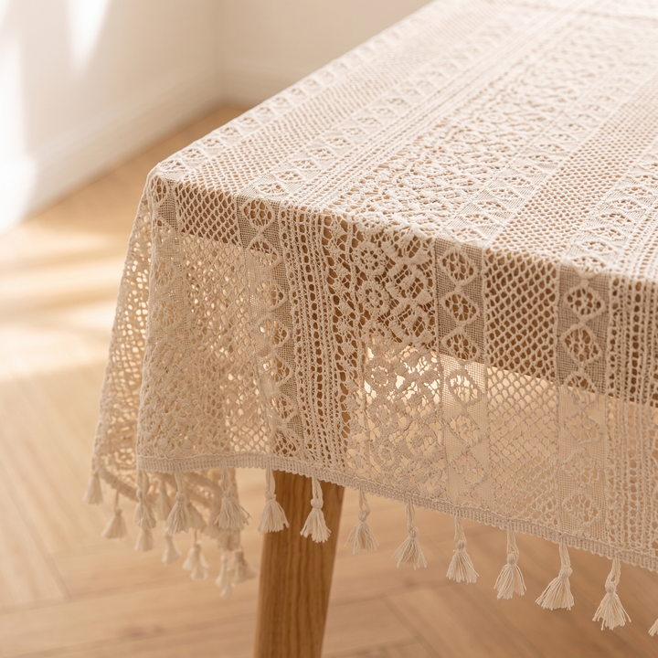Lace Tablecloth with Tassels in Cream – corner close-up draped over a wooden table beside a sunlit herringbone floor