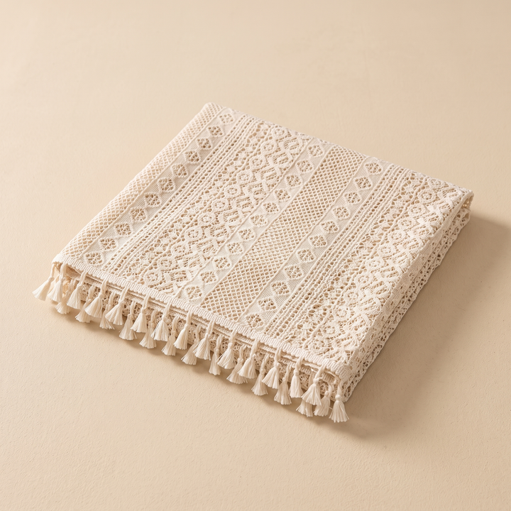 Lace Tablecloth with Tassels in Cream – folded neatly on a plain beige background, tassels along front edge