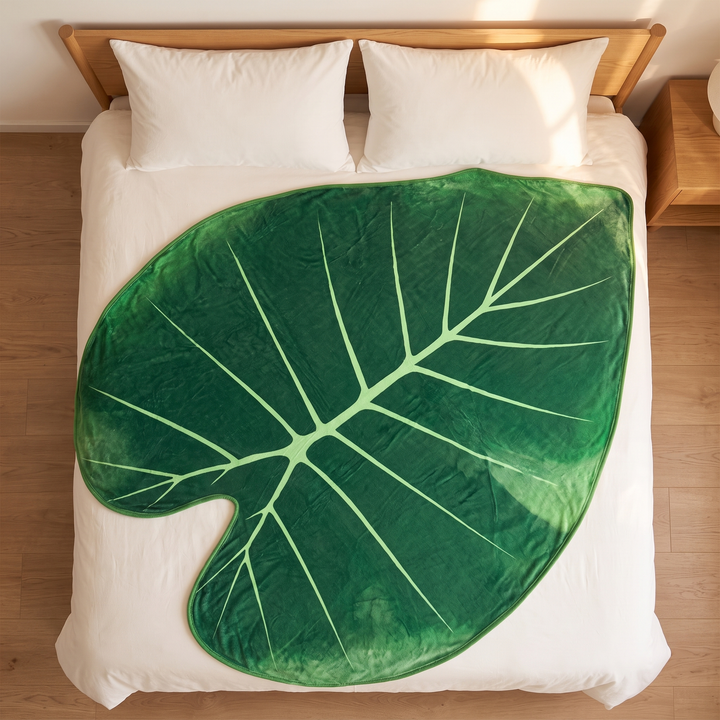 Leaf Blanket – Leaf-Shaped Flannel Throw in Dark Green – Heart Leaf – overhead view laid flat on white bedding below a wooden headboard