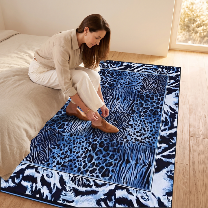 Leopard Print Rug – Washable in Blue – woman sitting on bed edge putting on shoes