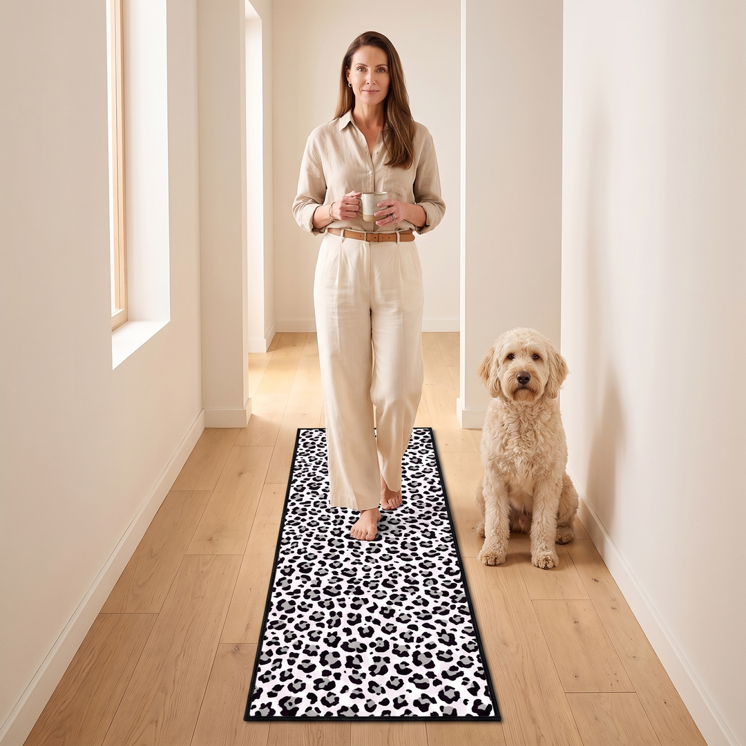 Leopard Print Runner Rug – Washable in White – in a bright hallway with a woman holding a mug and a seated dog