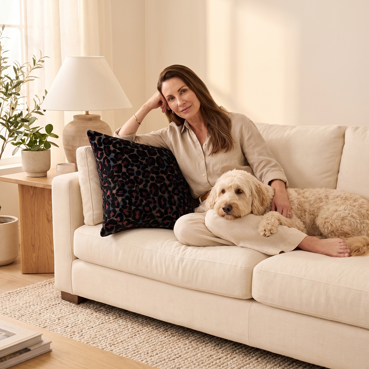 Leopard Print Velvet Pillow Cover in Black – beside a woman and fluffy dog on a sofa