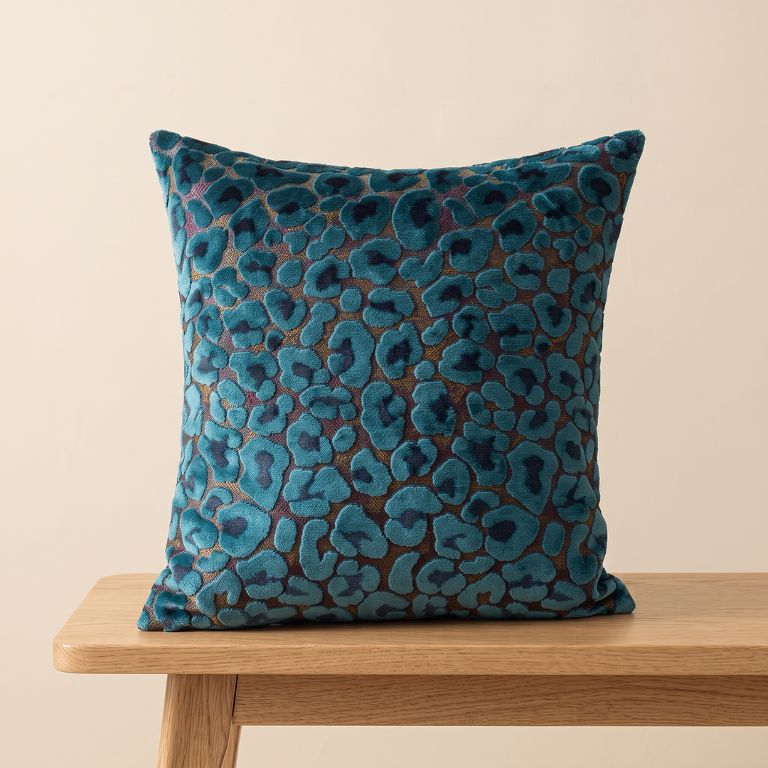 Leopard Print Velvet Pillow Cover in Teal – centered on a wooden bench with angled legs