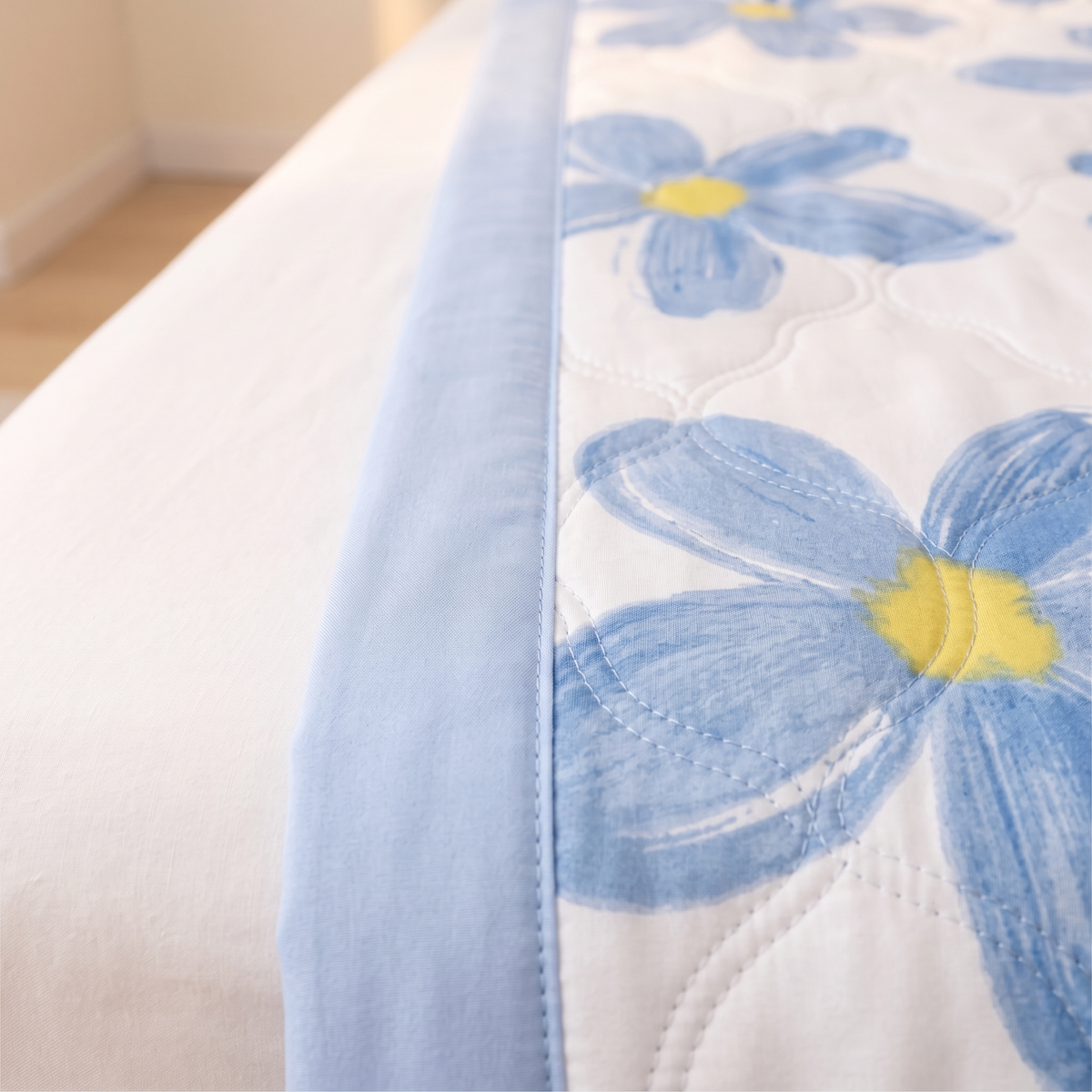 Lightweight Floral Quilt in Blue Floral – close-up of quilted edge with blue binding on a bed