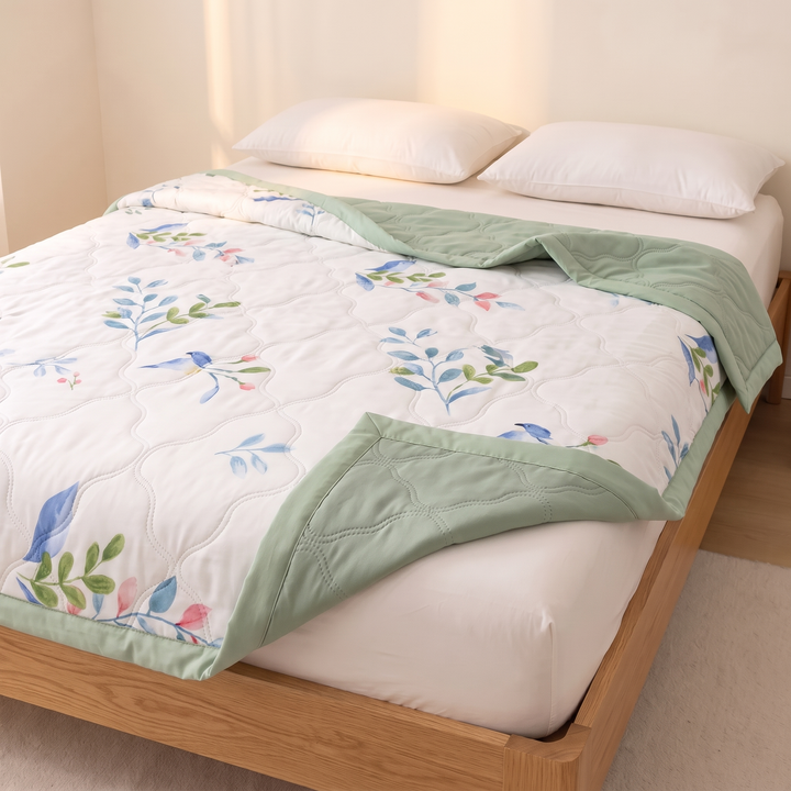 Lightweight Floral Quilt in Sage Botanical – angled view on an oak platform bed with two pillows
