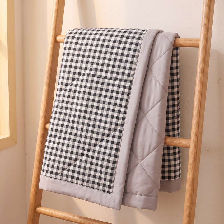 Lightweight Quilted Coverlet in Black Gingham – hung over a wooden ladder against a cream wall