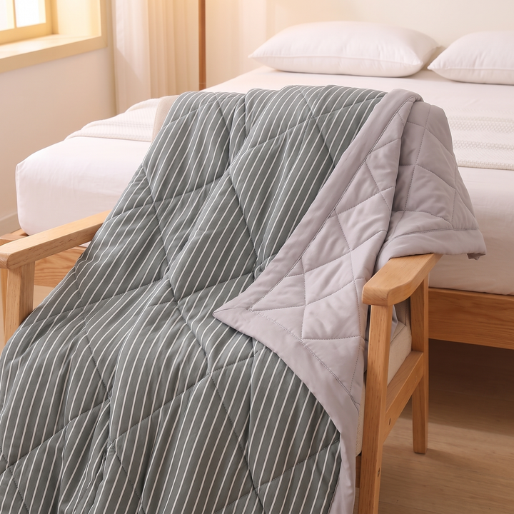 Lightweight Quilted Coverlet in Charcoal Stripe – draped over a wooden armchair beside a bed