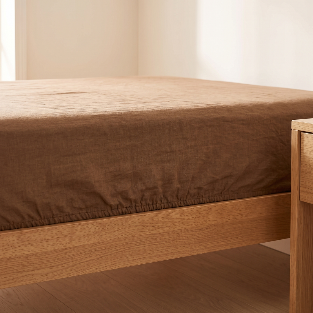 Linen Fitted Sheet – Deep Pocket in Brown – low side view beside an oak nightstand and wood floor