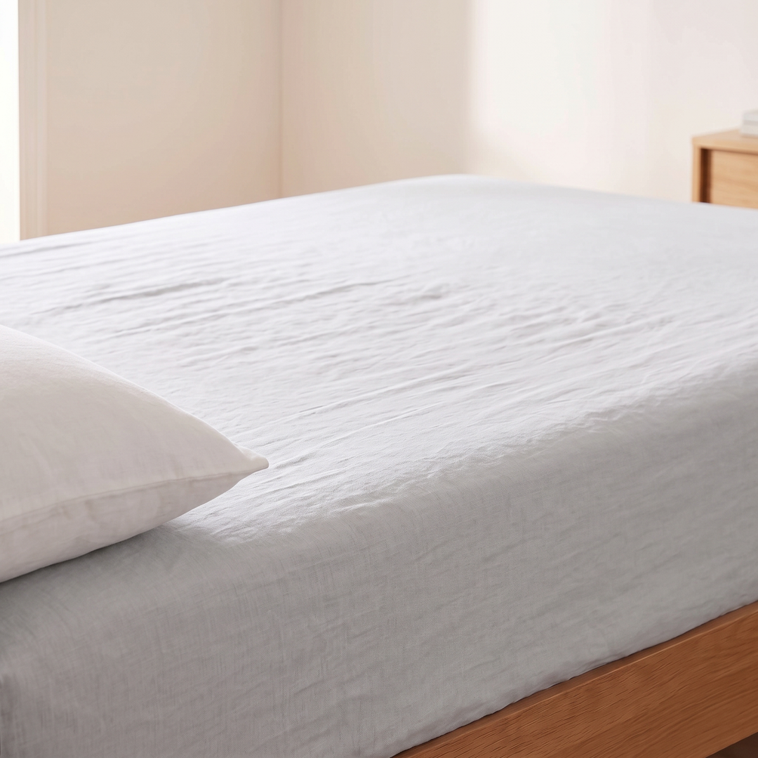 Linen Fitted Sheet – Deep Pocket in Light Gray – stretched over a mattress with a pillow resting at one side