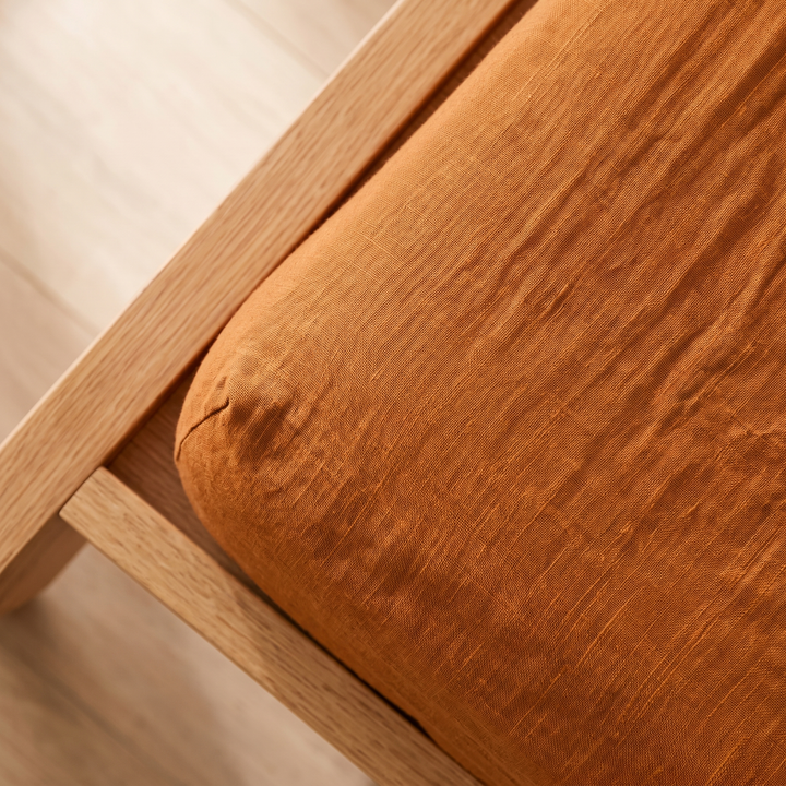 Linen Fitted Sheet – Deep Pocket in Orange – tight crop of crinkled weave beside oak rail