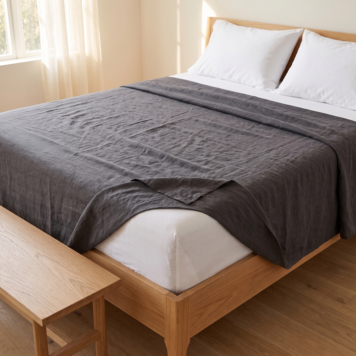 Linen Flat Sheet – Stone-Washed in Charcoal – spread across oak bed with bench at foot