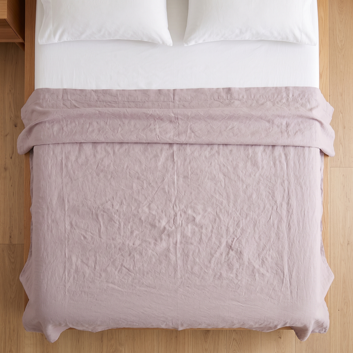 Linen Flat Sheet – Stone-Washed in Mauve – top-down view over wooden bed frame and oak floor