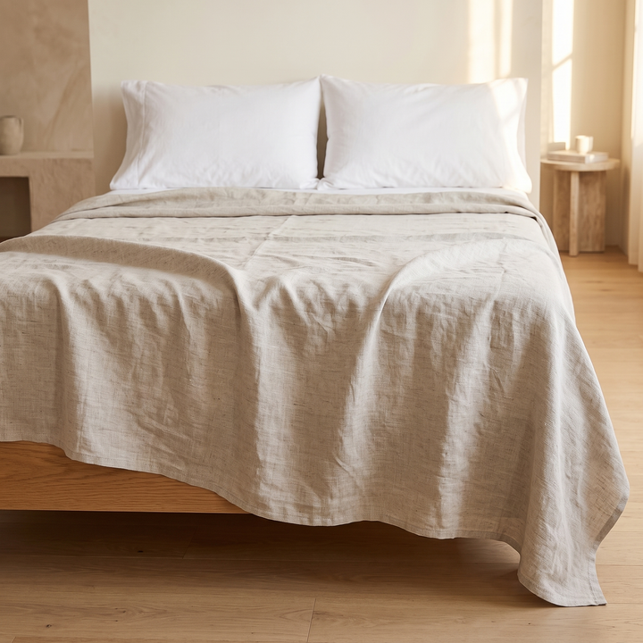 Linen Flat Sheet – Stone-Washed in Oatmeal – wide front view on made bed beside wooden side table