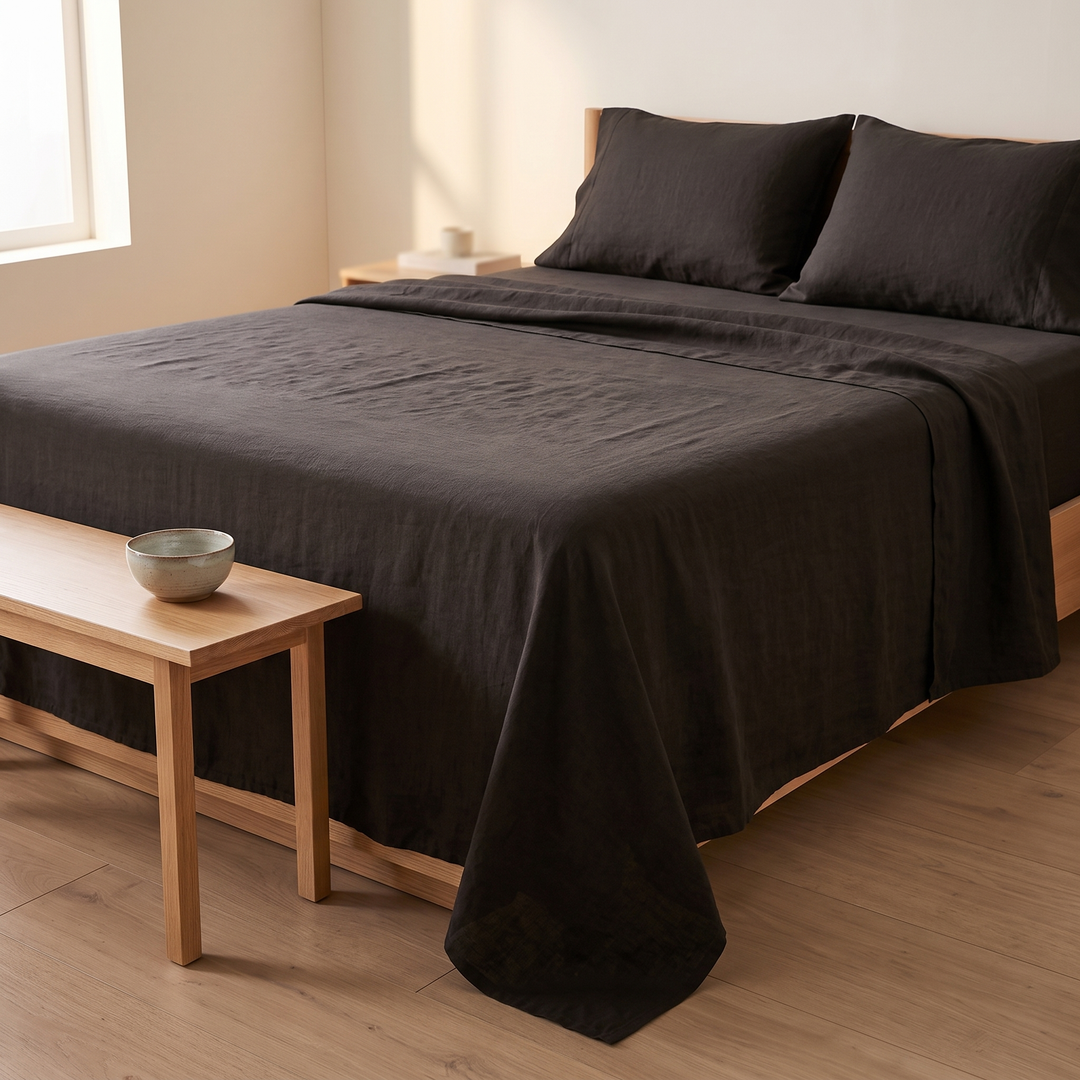 Linen Flat Sheet Set – Stone-Washed, with 2 Pillowcases in Black – bed seen past a wooden bench holding a bowl