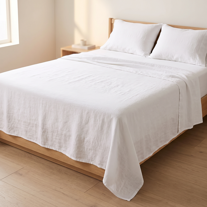 Linen Flat Sheet Set – Stone-Washed, with 2 Pillowcases in White – on a made bed with wooden frame in sunlit bedroom