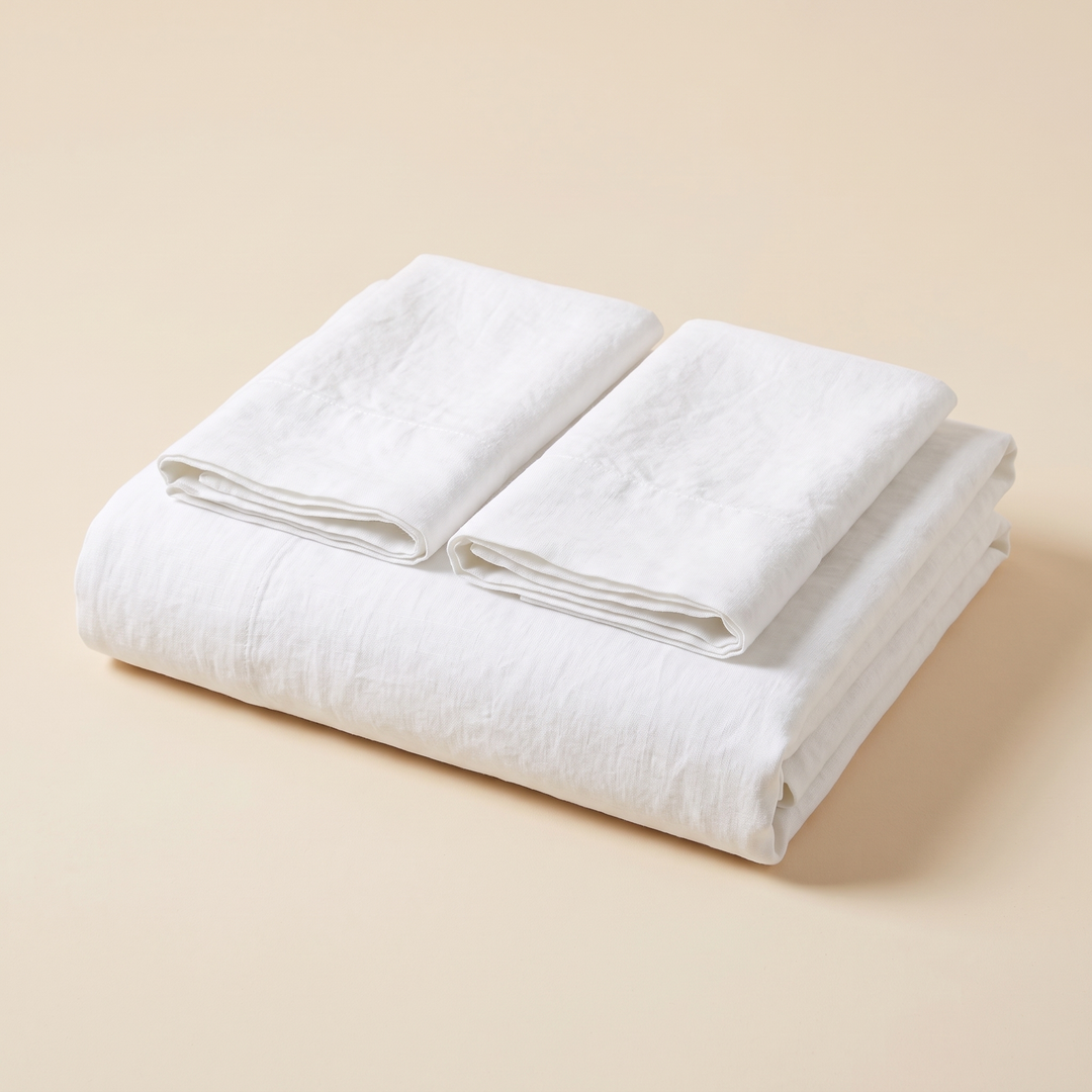 Linen Flat Sheet Set – Stone-Washed, with 2 Pillowcases in White – folded stack with two pillowcases on top, against a plain peach background
