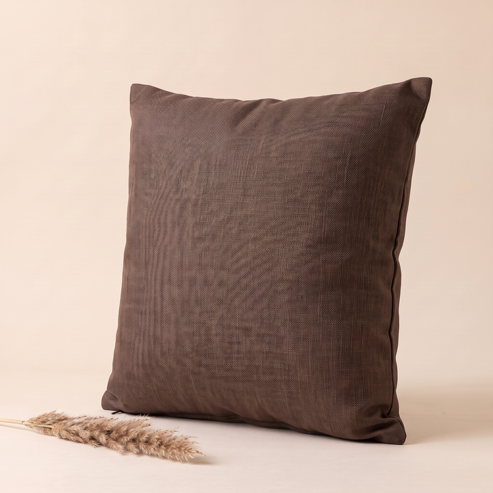 Linen-Look Pillow Cover in Chocolate Brown – angled view with a dried grass plume lying in front