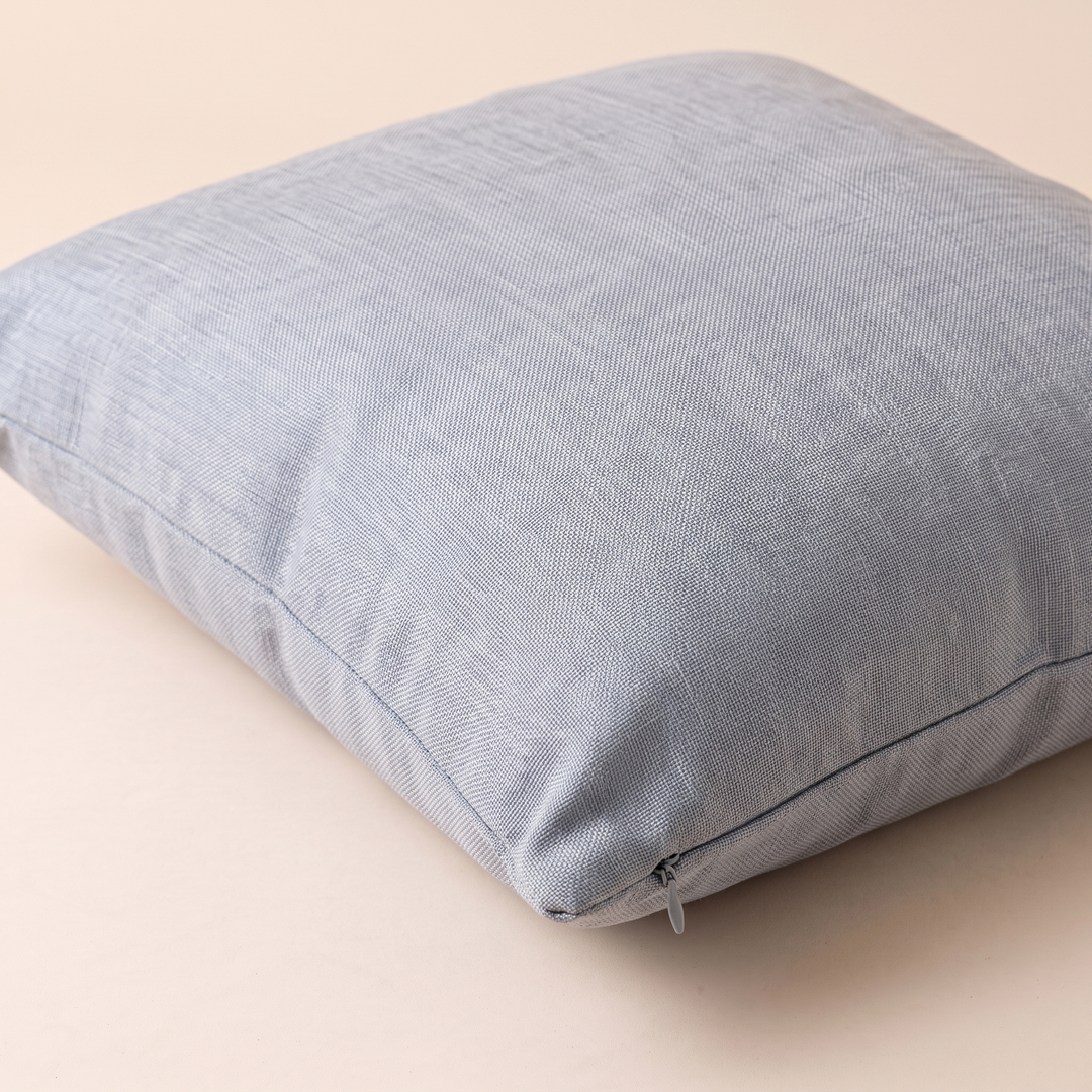 Linen-Look Pillow Cover in Light Gray – lying flat on a peach surface, seen from above at an angle