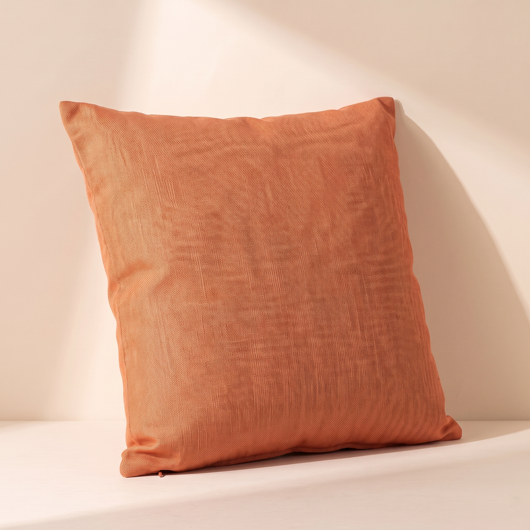 Linen-Look Pillow Cover in Orange – leaning against a sunlit wall casting a long shadow