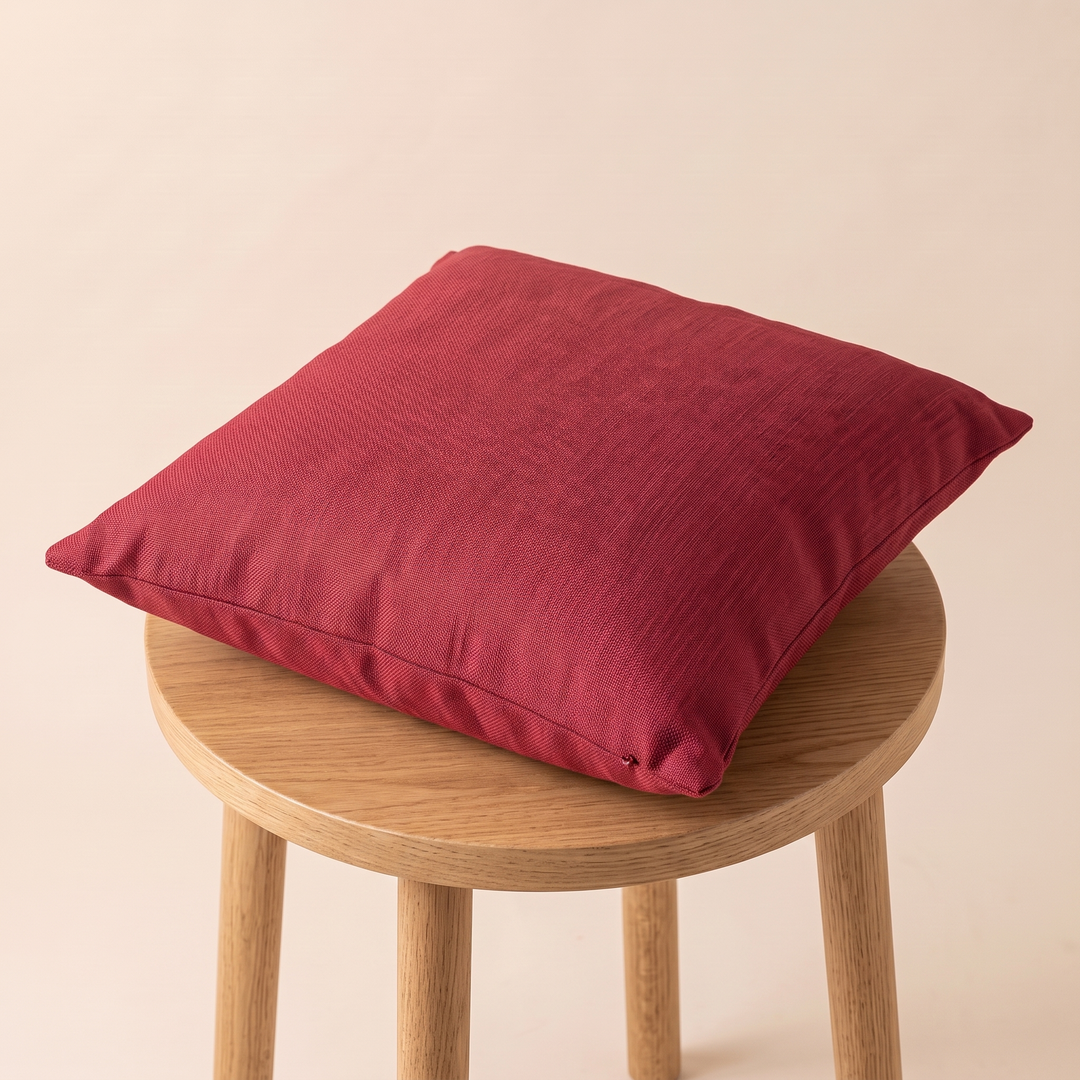 Linen-Look Pillow Cover in Red – lying flat on top of a round wooden stool