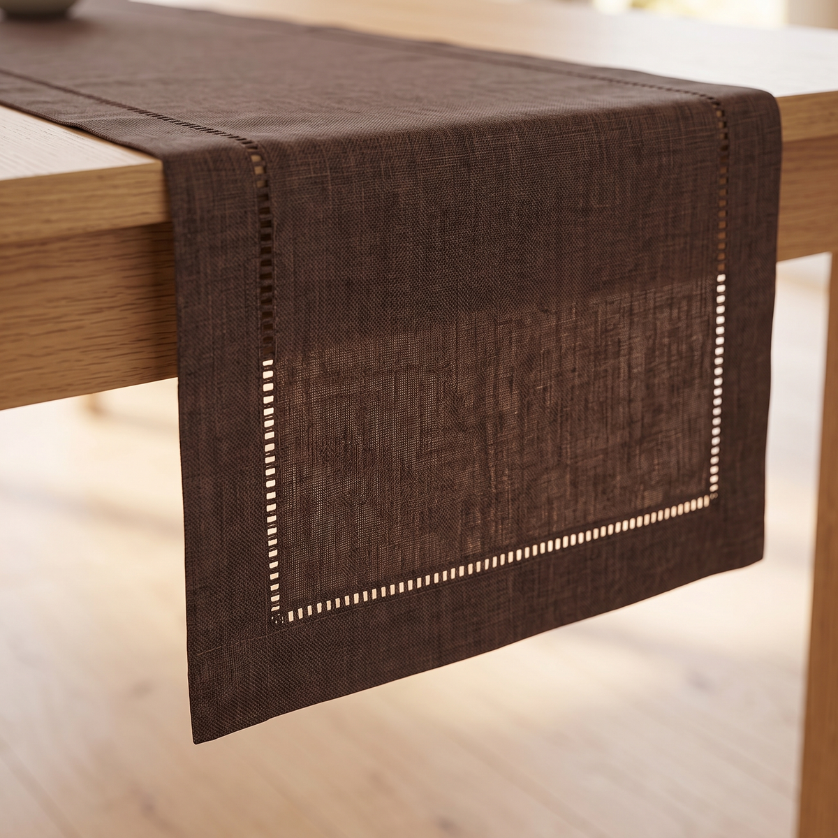 Linen-Look Table Runner – Hemstitch Border in Chocolate Brown – end of runner hanging over wooden table edge, hemstitch detail visible