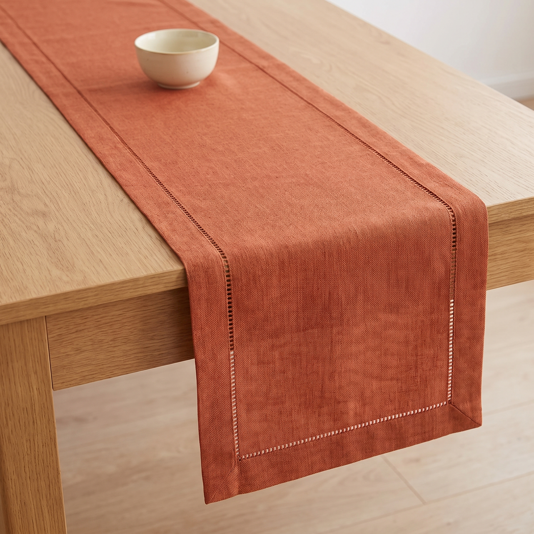 Linen-Look Table Runner – Hemstitch Border in Rust – single small bowl on runner, light wood floor beneath