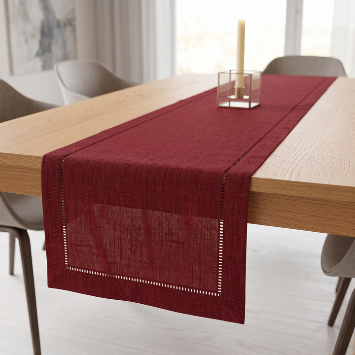 Linen-Look Table Runner – Hemstitch Border in Burgundy – with a taper candle in glass holder, gray chairs behind
