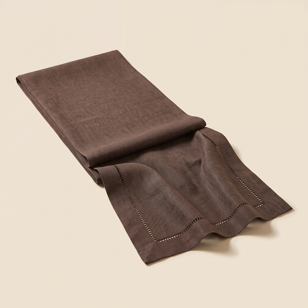 Linen-Look Table Runner – Hemstitch Border in Chocolate Brown – folded lengthwise on a plain cream background, one end unfolded