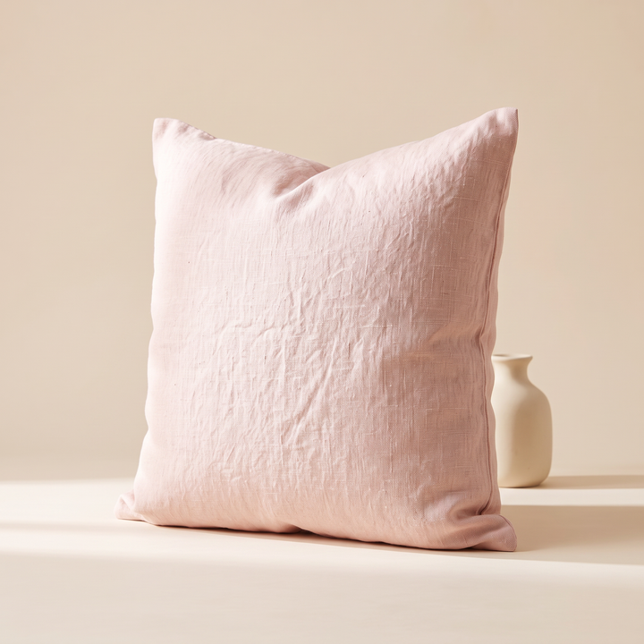 Linen Pillow Cover – 100% Linen in Light Pink – upright beside a rounded ceramic vase in soft sunlight and shadow