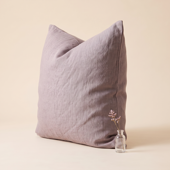 Linen Pillow Cover – 100% Linen in Mauve – three-quarter view beside a small glass bottle holding dried flowers