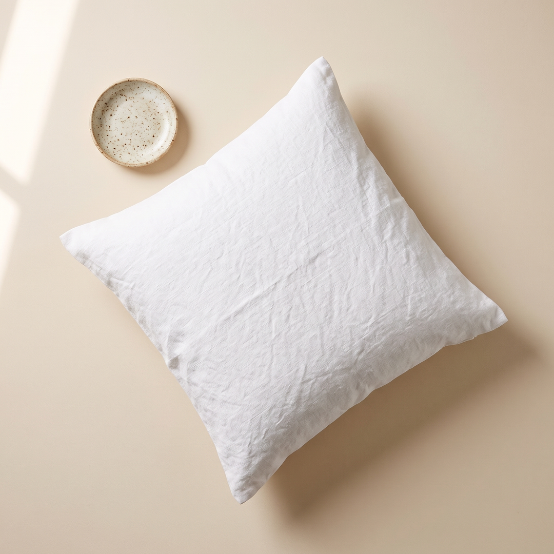 Linen Pillow Cover – 100% Linen in White – flat lay from above on a cream surface beside a speckled ceramic dish