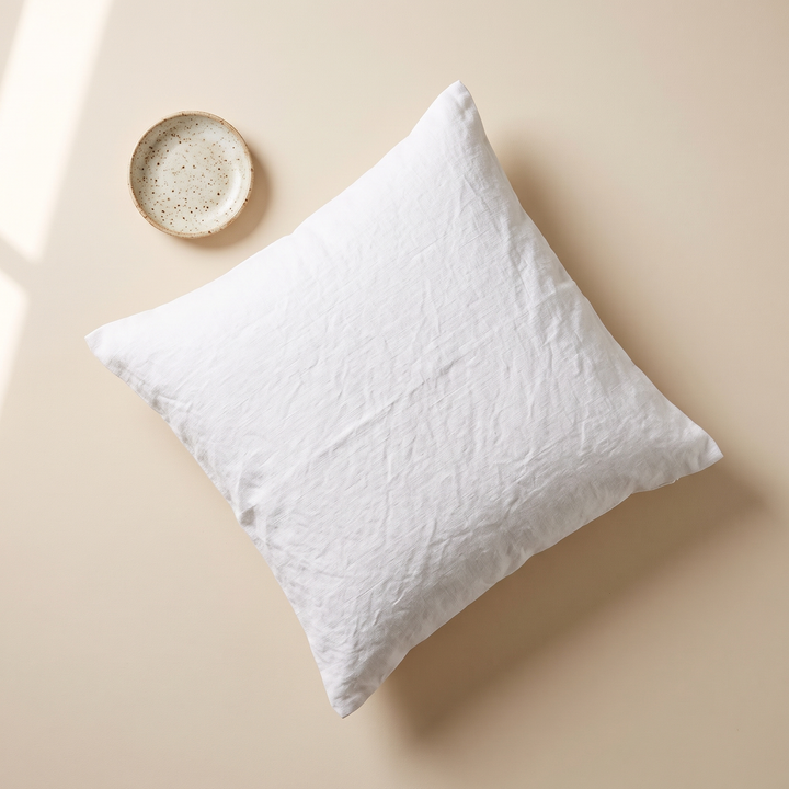 Linen Pillow Cover – 100% Linen in White – flat lay from above on a cream surface beside a speckled ceramic dish