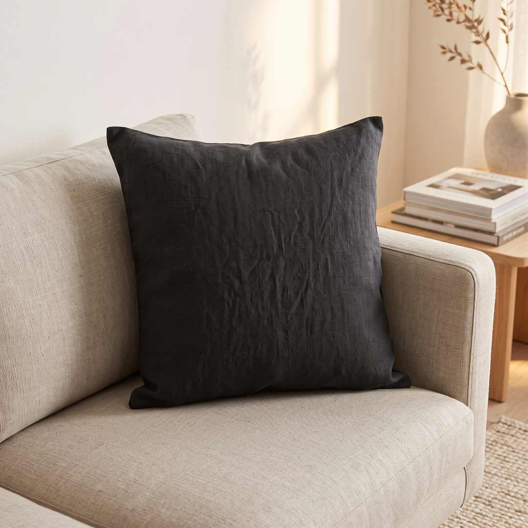 Linen Pillow Cover – 100% Linen in Black – propped on a beige sofa beside a wooden side table