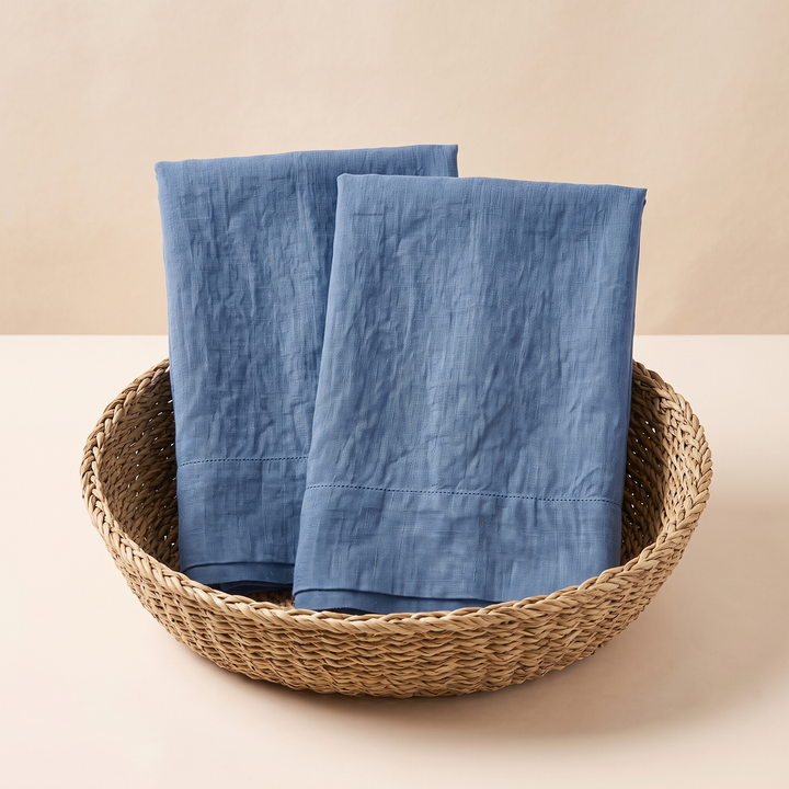 Linen Pillowcases – Set of 2 in Blue – two upright folded pieces standing in a woven round basket