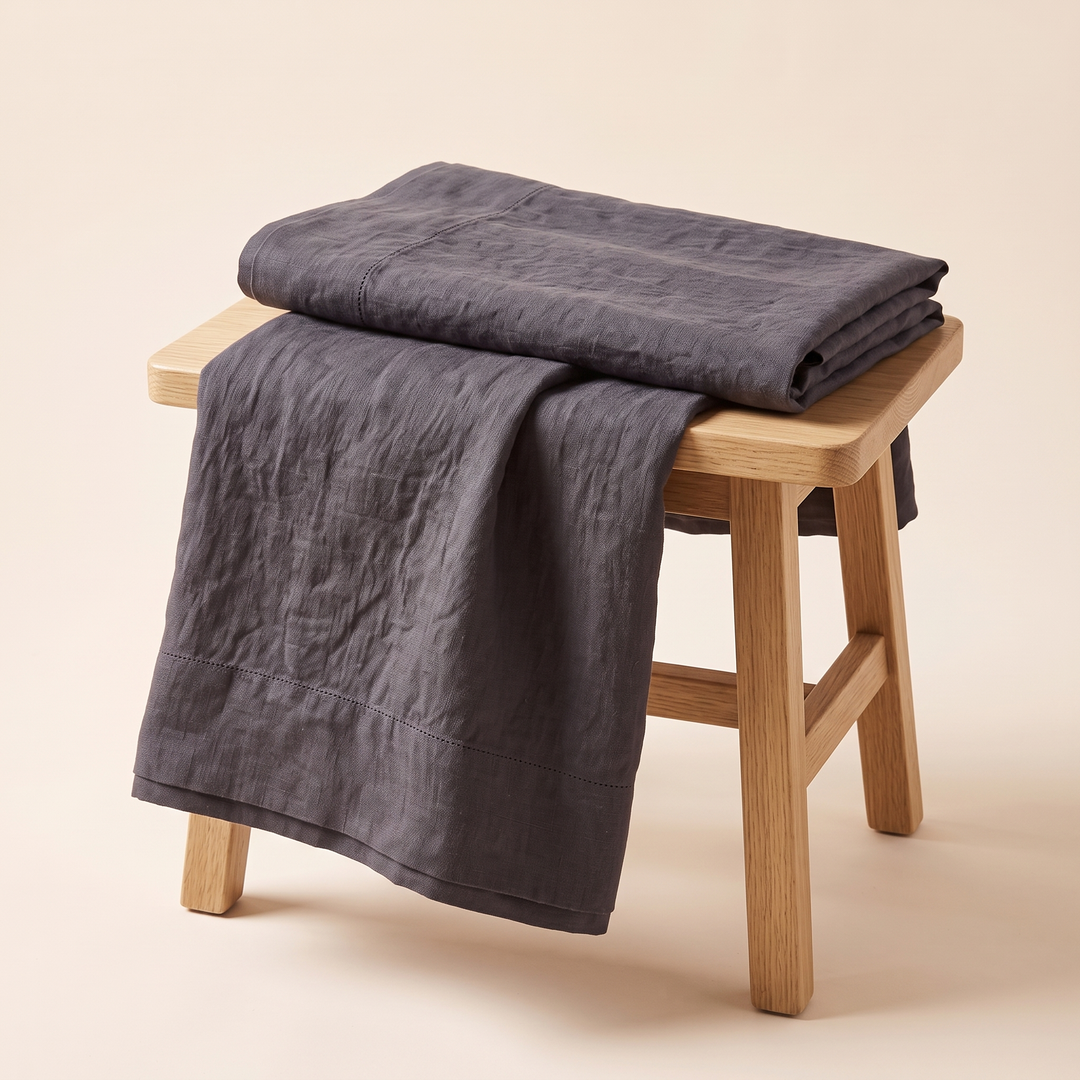 Linen Pillowcases – Set of 2 in Dark Gray – folded stack on wooden stool with one draped over the side